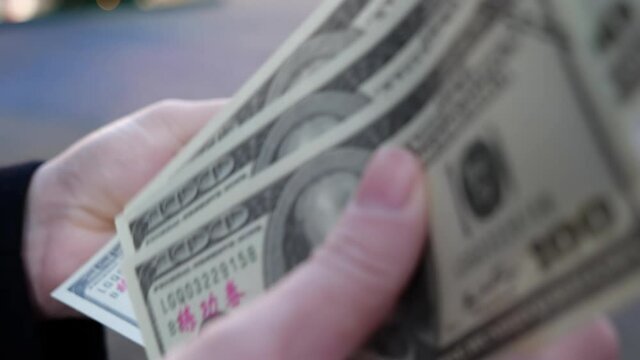 Close up of woman's hands counting a stack of 100 dollar bills USD