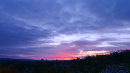 Amazing sunrise in rural scene. Dramatic sky with sunbeam and stratus clouds over the silhouette of hill on the horizon.