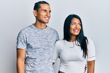 Young latin couple wearing casual clothes smiling looking to the side and staring away thinking.