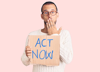 Young handsome man holding act now banner covering mouth with hand, shocked and afraid for mistake....