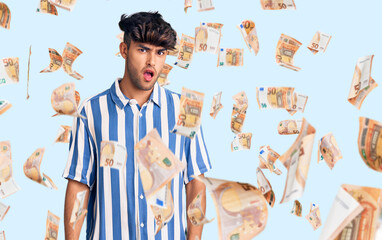 Young hispanic man wearing casual clothes in shock face, looking skeptical and sarcastic, surprised...