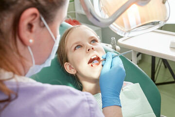 Child to the dentist. Child in the dental chair dental treatment during surgery. Small kid patient visiting specialist in dental clinic.