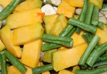 many pieces of pumpkin, raw banana, french beans, on the plate with vegetable background