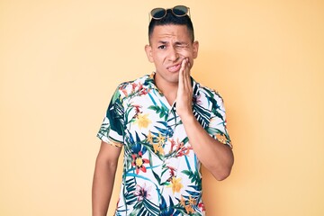 Young handsome latin man wearing summer clothes touching mouth with hand with painful expression because of toothache or dental illness on teeth. dentist