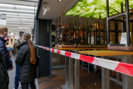 Selected focus view at Red and white caution tape restrict dining area and people queue for take away order at Carlsplatz market in Düsseldorf, Germany during lockdown by epidemic COVID-19. 