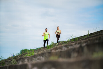 Athletic couple running marathon on stairs. Workout in urban outdoor. Jogging people training outside.