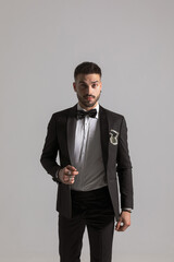 young male model in black tuxedo holding arm in a fashion pose