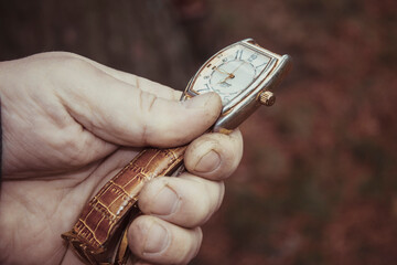 Stylish vintage mechanical wrist watch on a brown leather strap in the hand of man