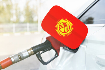 Flag of Kyrgyzstan on the car's fuel filler flap with gas pump nozzle in the tank.
