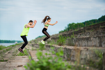 Athletic young couple exercizing jumping on stairs outdoor, couple workout. Active lifestyle in...