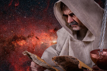 An elderly bearded man in monastic clothes studies ancient secret manuscripts on a birch bark,...