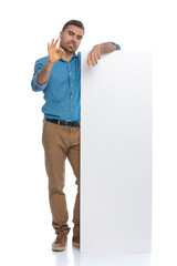sexy casual man leaning on a long billboard