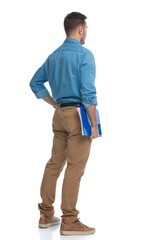 young casual man holding a blue clipboard and pondering something
