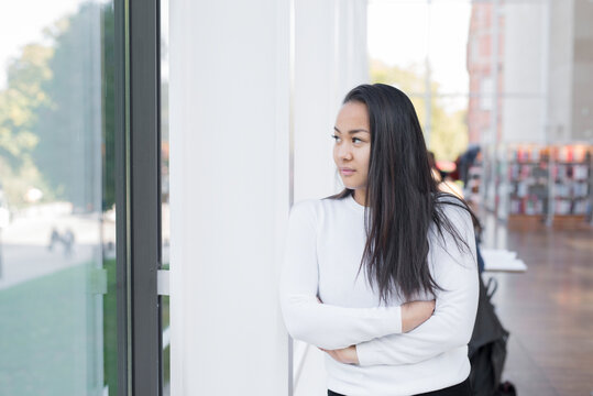 Young woman looking through window, Sweden