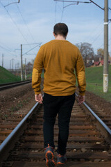 Photo of a young and attractive man walking alone in an abandoned railway during a sunny day