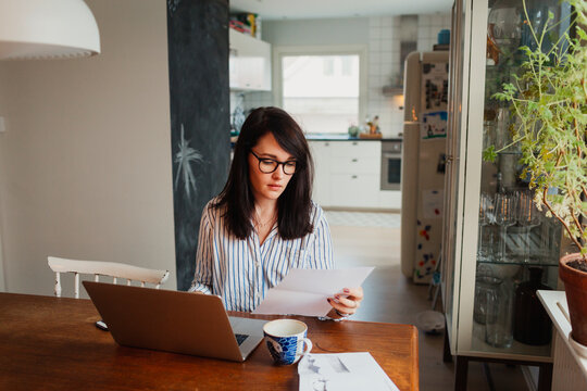 Woman with laptop in dining room, Sweden