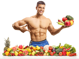 Obraz premium Topless male fitnes model posing with a plate of fruits and vegetables and pointing at his abs