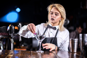Professional woman bartender formulates a cocktail at the nightclub