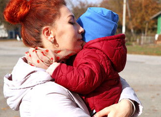 girl holding a child in her arms. Mother and son. Red-haired girl. parental love and mother's hug