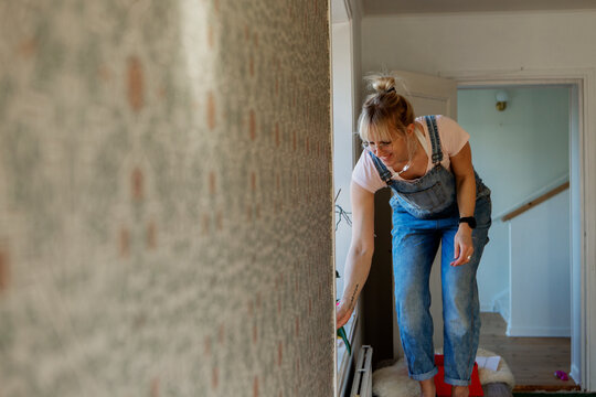 Woman sticking wallpaper on wall, Sweden