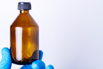hand in a nitrile glove holds a bottle brown glass