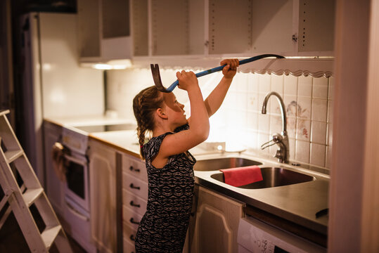 Girl dismantling kitchen cupboards, Sweden
