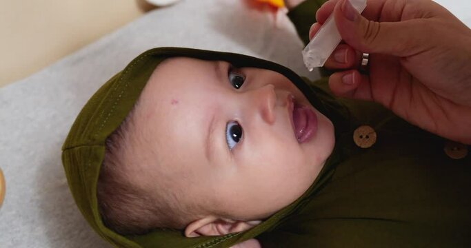 Cute little baby taking rotavirus vaccine drop from pipette.