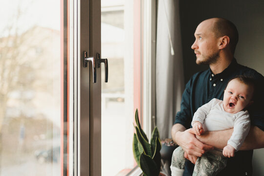 Father with baby looking through window, Sweden