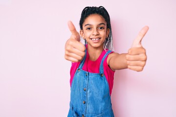 Young african american girl child with braids wearing casual clothes over pink background approving...