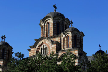Fototapeta na wymiar Front view of St. Mark's orthodox church amid trees in Tasmajdan park, during a sunny autumn day in Belgrade, Serbia.