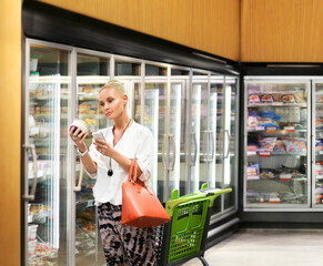 Woman choosing frozen food from a supermarket freezer