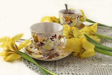 Yellow irises with two cups of tea on a gray napkin, side view, space for text-the concept of pleasant meetings and a wonderful time