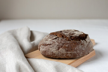 Black rye bread on a wooden board on a light background