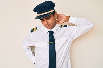 Young hispanic man wearing airplane pilot uniform suffering of neck ache injury, touching neck with hand, muscular pain © Krakenimages.com