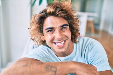Fototapeta premium Young hispanic man smiling happy sitting on the sofa at home