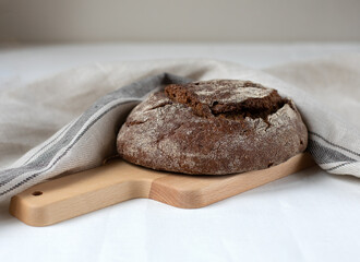 Black rye bread on a wooden board on a light background
