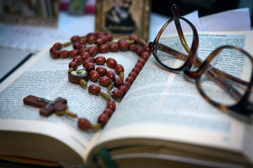 Open Holy Bible with rosary and glasses on top