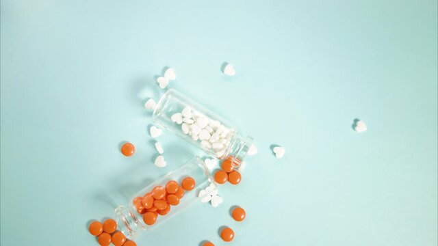 Stop motion video. Two glass jars on the table, from which pills pour out.