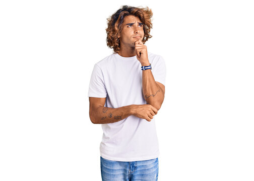 Young hispanic man wearing casual white tshirt thinking worried about a question, concerned and nervous with hand on chin