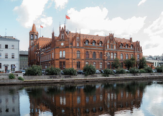 Fototapeta premium Polish Post Office House in Bydgoszcz. Ancient building above the canal. Red brick building.