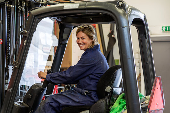 Woman driving forklift truck in warehouse, Sweden