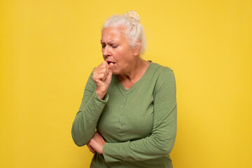 Senior woman feeling unwell and coughing as symptom for cold or bronchitis