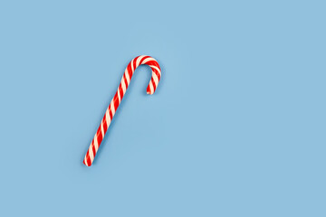 Mint hard candy cane striped in Christmas colours on blue background. Closeup.
