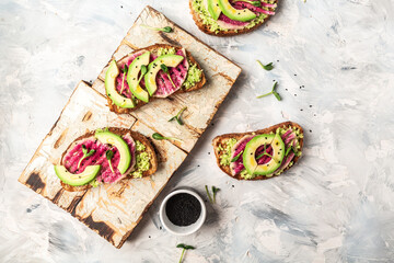 Vegan sandwiches with avocado, watermelon radish and tomatoes on a black background. Flat lay. Top view
