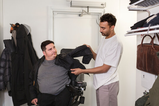 Career helping man in wheelchair putting jacket on, Sweden