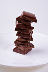 vertical pyramid of pieces of dark chocolate on a white plate.
