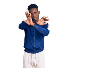 Young african american man wearing sportswear rejection expression crossing arms doing negative sign, angry face
