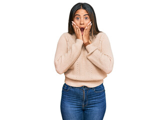 Young latin girl wearing wool winter sweater afraid and shocked, surprise and amazed expression with hands on face