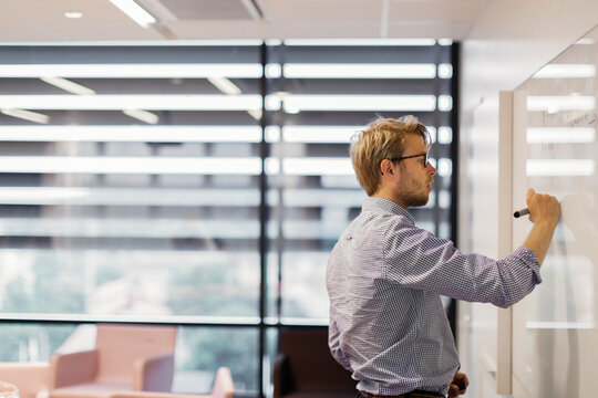 Businessman writing on whiteboard in office, Sweden