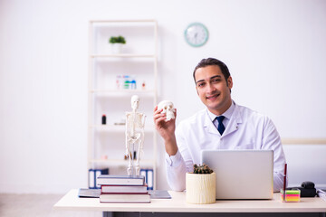 Young male doctor studying human skeleton